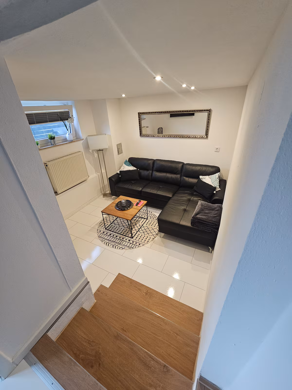 Wohnzimmer mit Ledercouch und Holztreppe